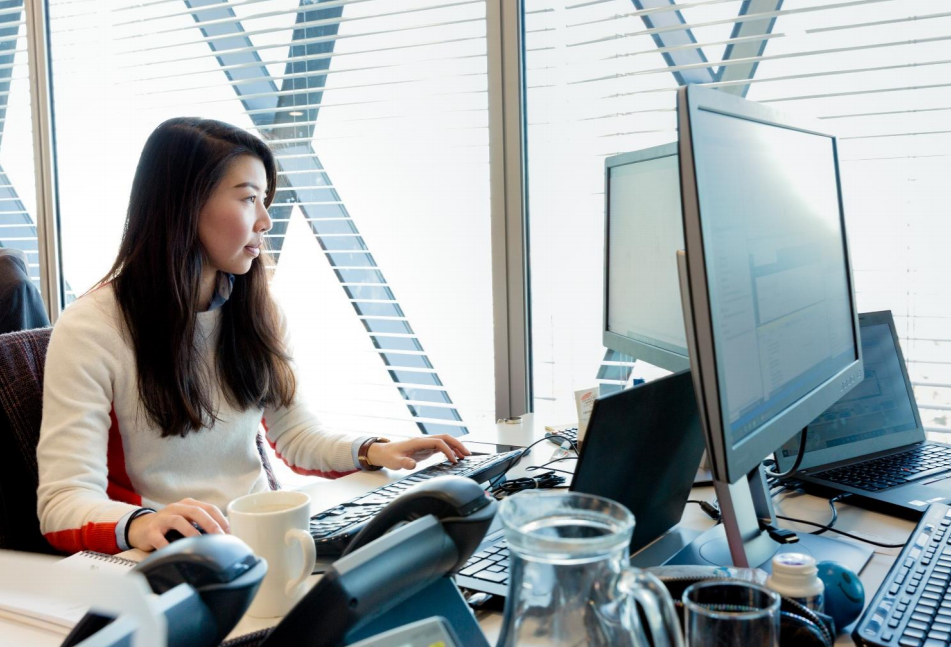 Person sitting at an office desk in front of a laptop and monitor.
