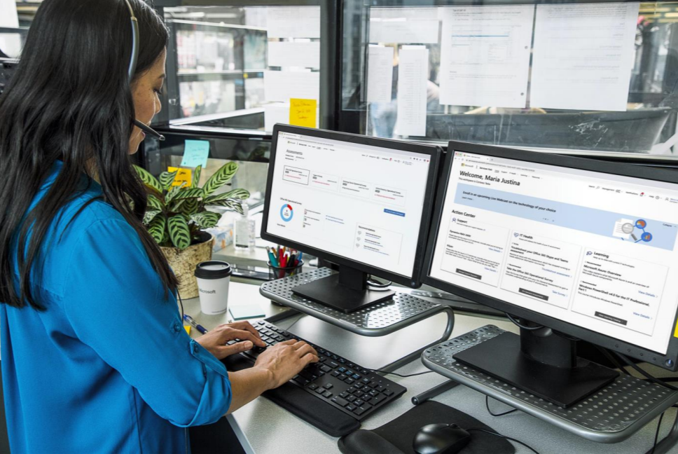 Person standing at an office desk with two monitors next to each other.